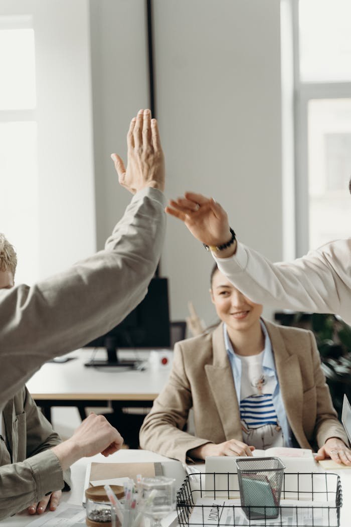 Colleagues in an office exchanging a high five, symbolizing teamwork and success.